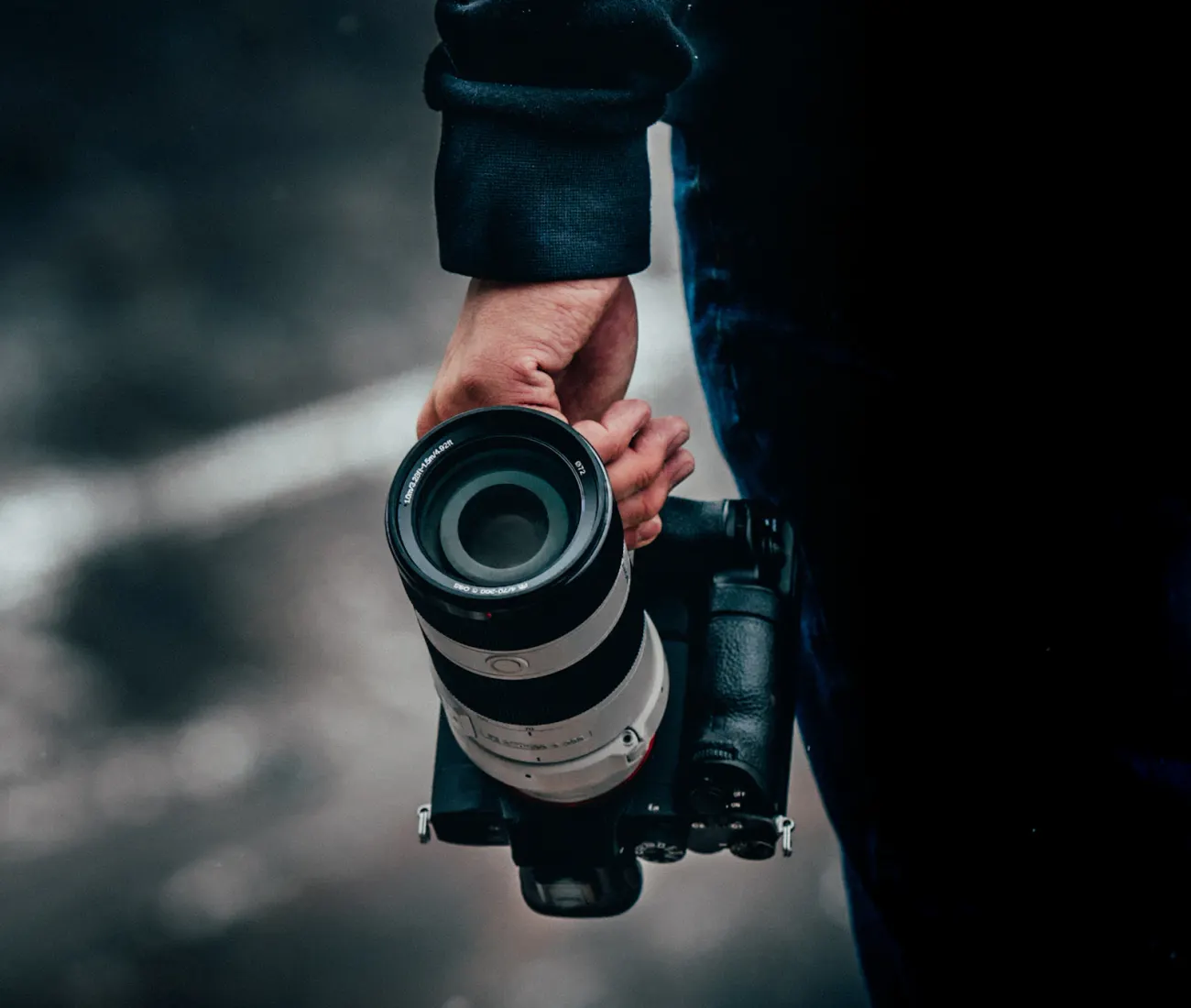 A photographer holding a Sony Alpha camera outdoors